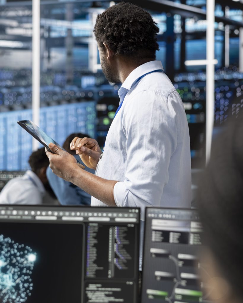 Data center admin uses AI visualization technology on tablet to oversee automated repetitive tasks. Server farm IT professional modifying infrastructure rigs systems based on data analytics graphs